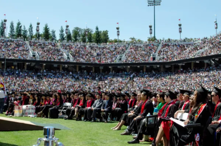 A crowded auditorium with students in robes and stoles.